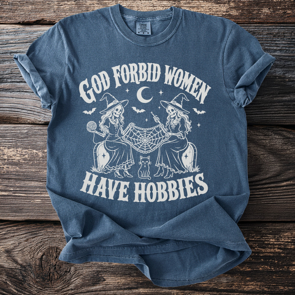 Blue t-shirt with "God Forbid Women Have Hobbies" text, two witches, and a cat.