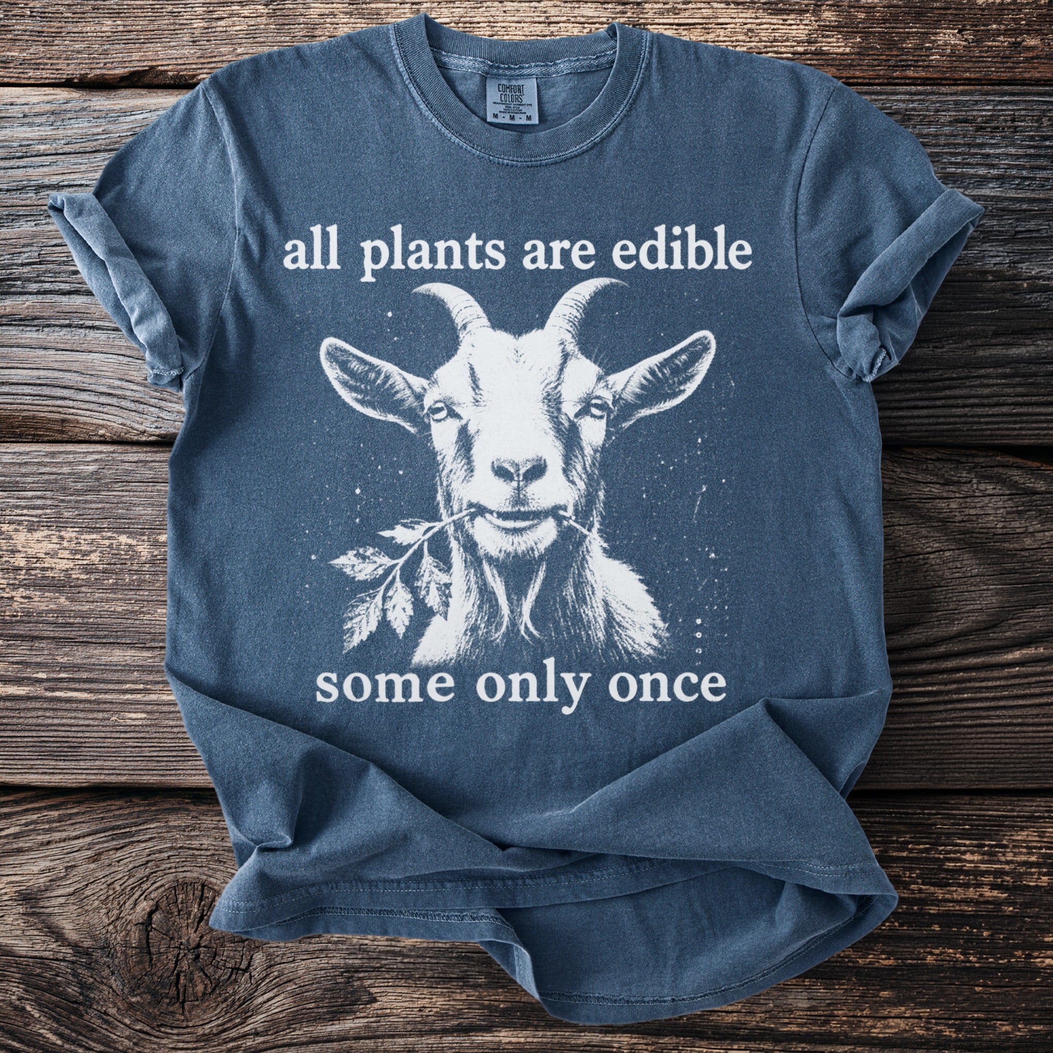 Blue t-shirt with a white graphic of a goat eating a leaf and text.