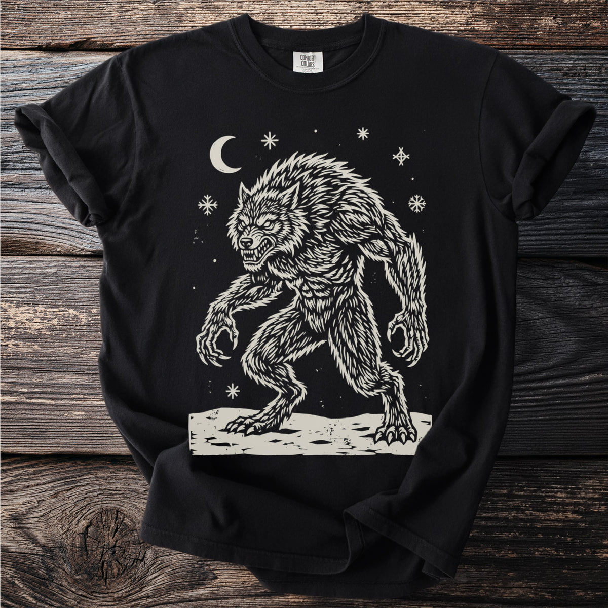 Black t-shirt with a cream folk-cut print: a hunched werewolf, teeth bared and claws out, stands in the snow under a crescent moon.