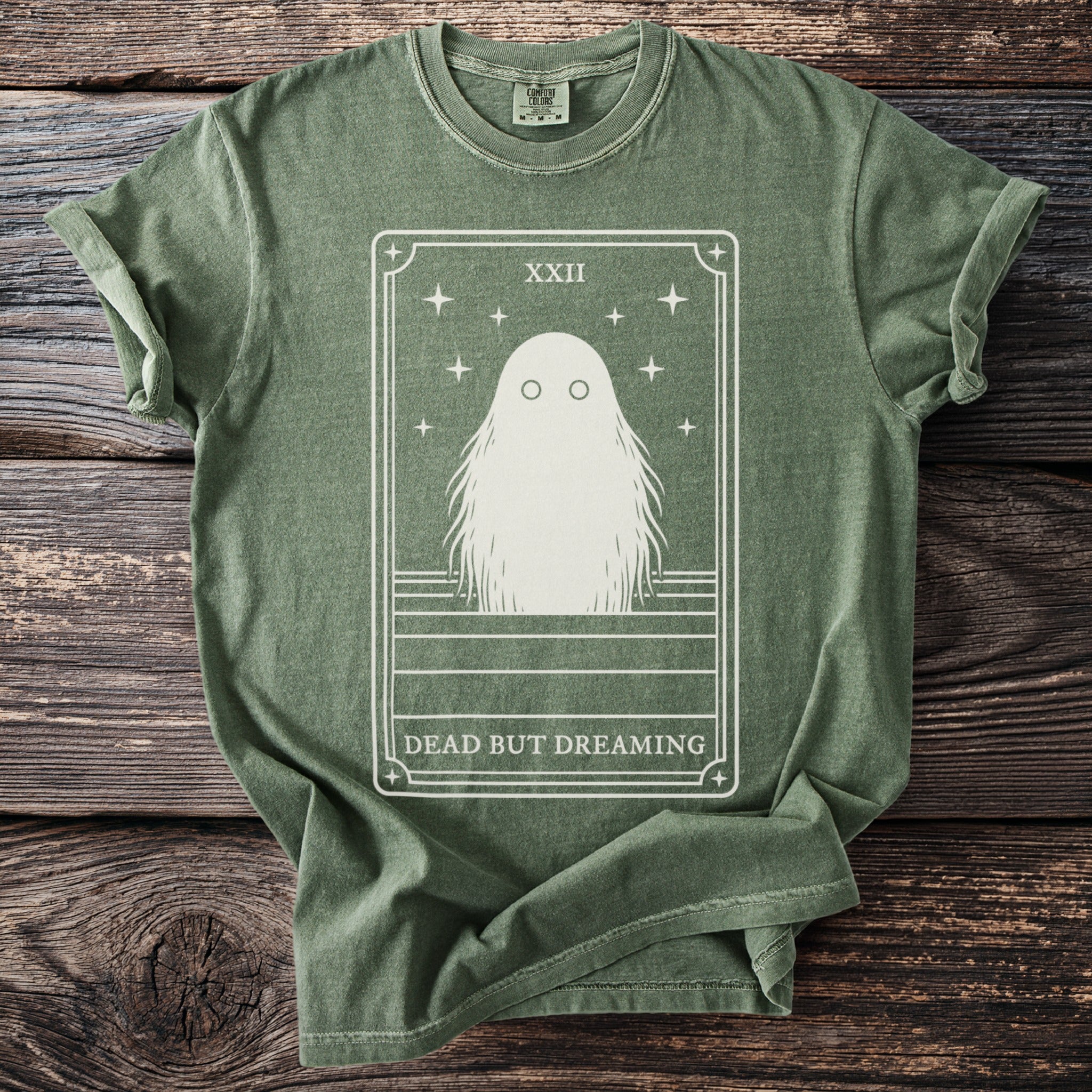Green t-shirt with a tarot card design featuring a ghost and "DEAD BUT DREAMING."