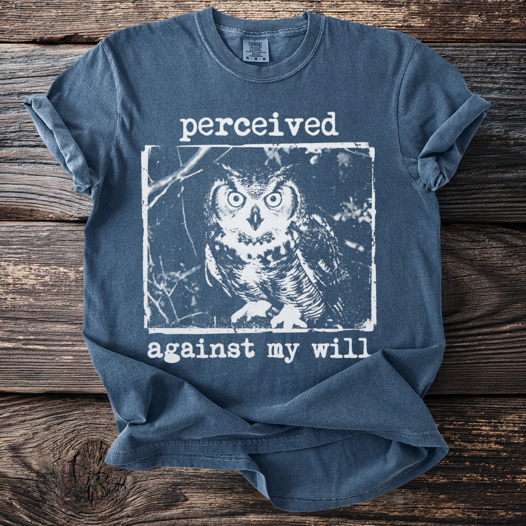 Blue t-shirt with a white distressed graphic of an owl and text reading "perceived against my will."