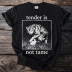 Black t-shirt with white text "tender is not tame" and wolf/rabbit illustration.