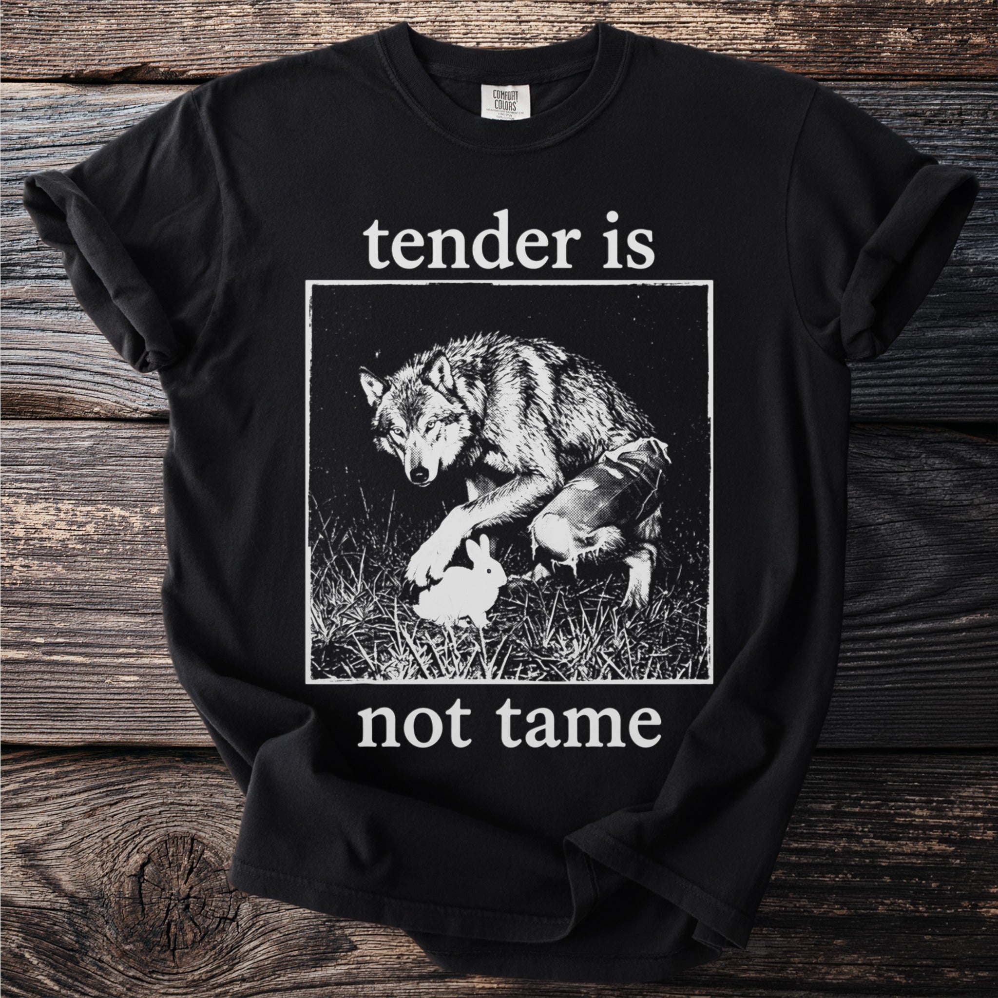 Black t-shirt with white text "tender is not tame" and wolf/rabbit illustration.