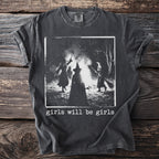 Dark gray t-shirt with a graphic of three witches around a bonfire and the text "girls will be girls".