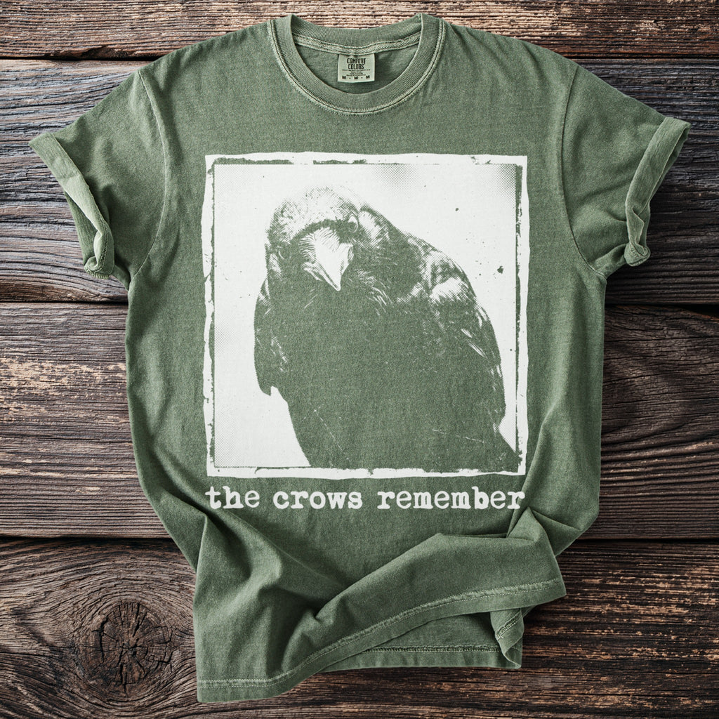 Green t-shirt with a distressed print of a crow and the text "the crows remember".