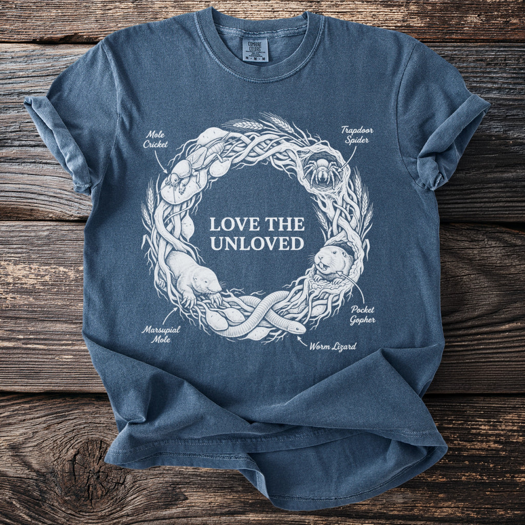 Blue t-shirt with central graphic "LOVE THE UNLOVED" and surrounding illustrated creatures.