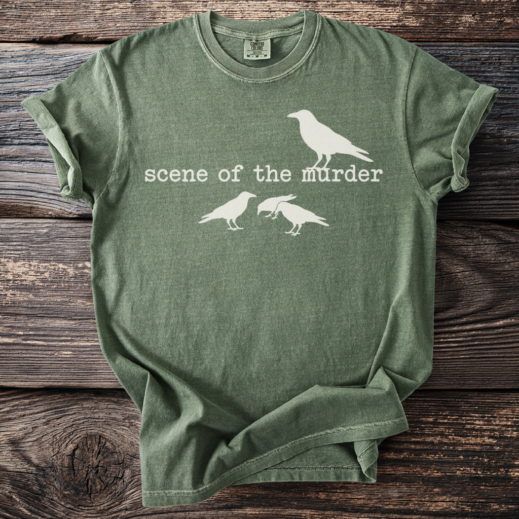 Green t-shirt with white text "scene of the murder" and three crows.