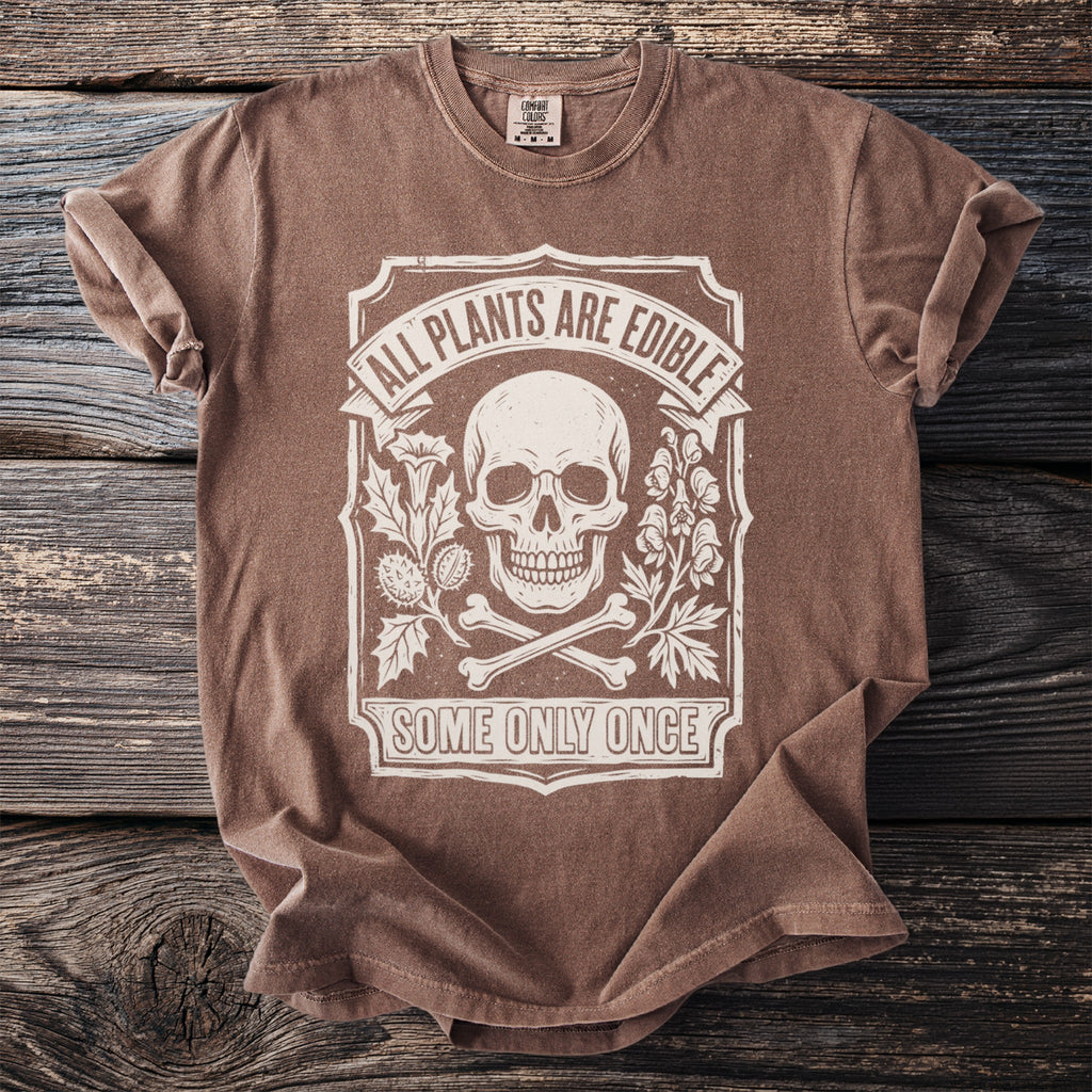 Brown t-shirt with white graphic of skull, bones, and plants; text says "All Plants Are Edible Some Only Once".