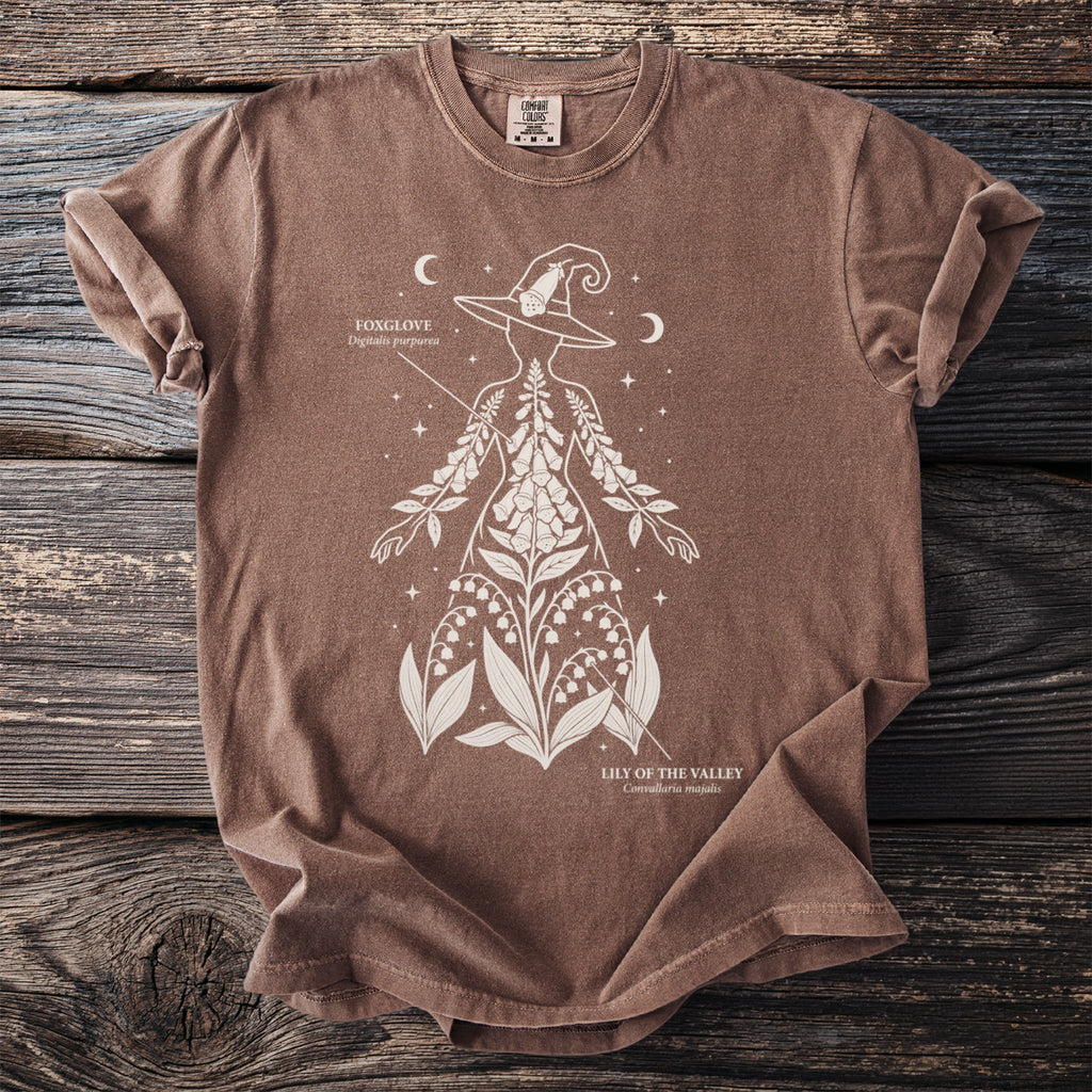 Brown t-shirt with white outline of a witch's silhouette filled with flowers.