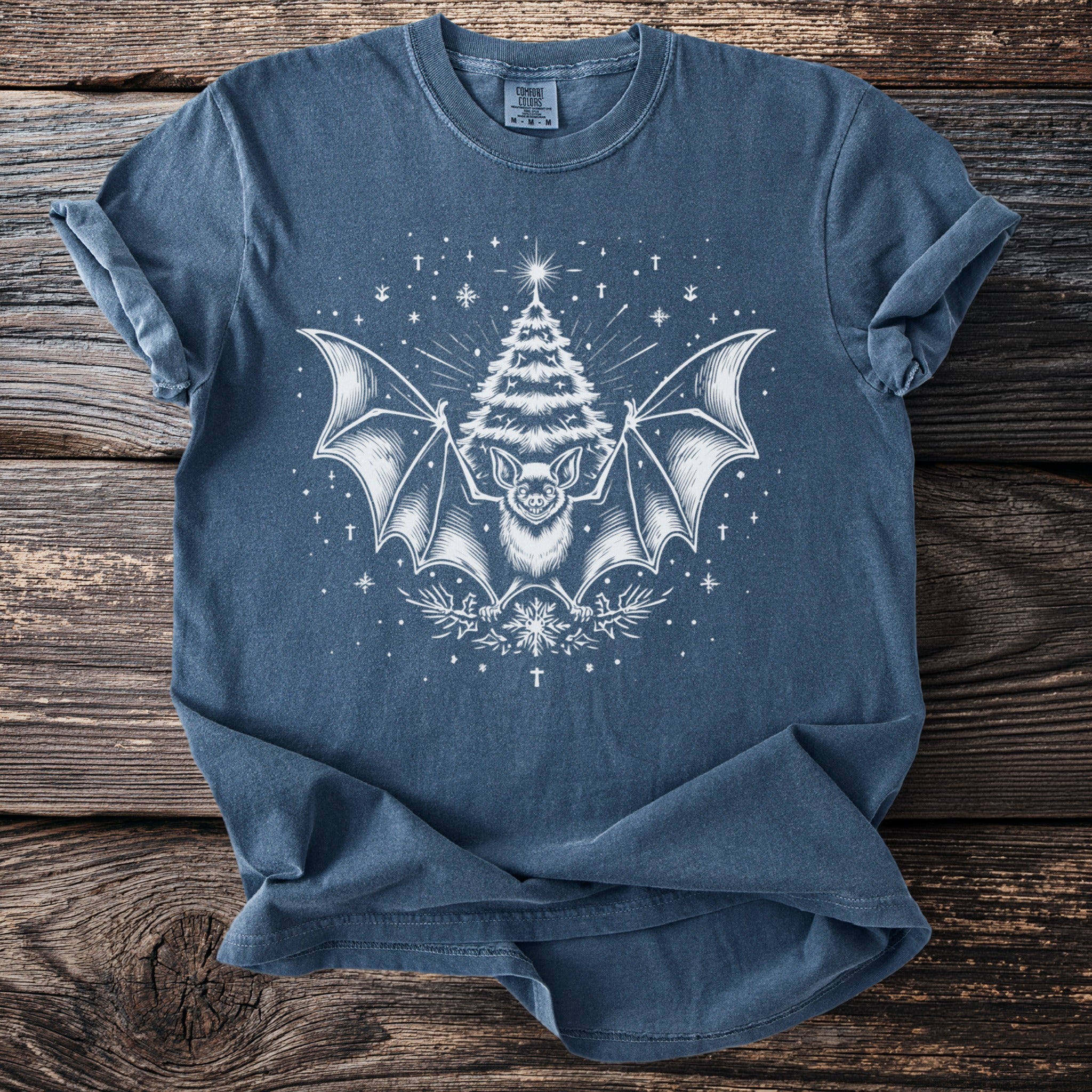 Blue t-shirt with white bat, Christmas tree, and snowflake graphic.
