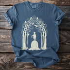 T-shirt with light beige graphic of a child holding a lantern on a stone, surrounded by trees and owls.