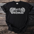 Black t-shirt with white gothic font text "Merry Gothmas" and floral skull accents.