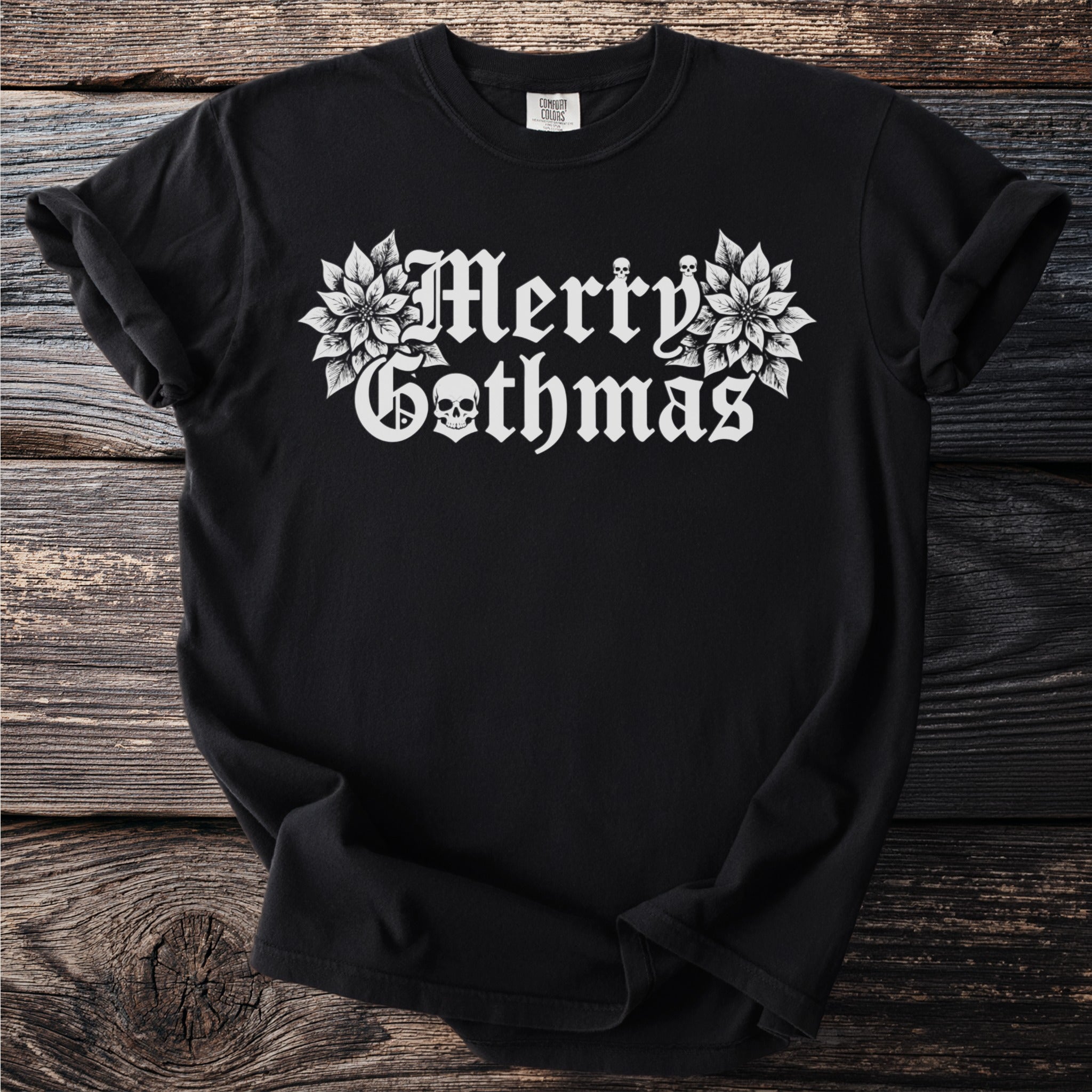 Black t-shirt with white gothic font text "Merry Gothmas" and floral skull accents.