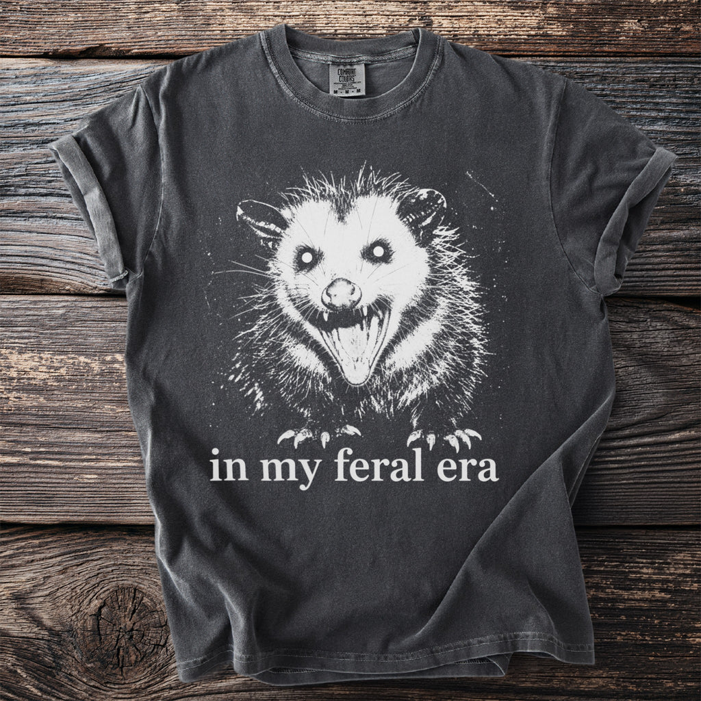 Dark gray t-shirt with white print of a snarling opossum and text "in my feral era".