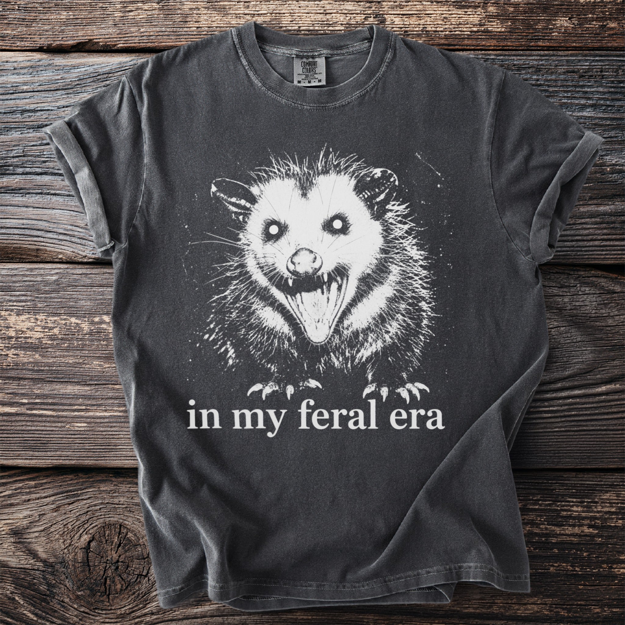 Dark gray t-shirt with white print of a snarling opossum and text "in my feral era".