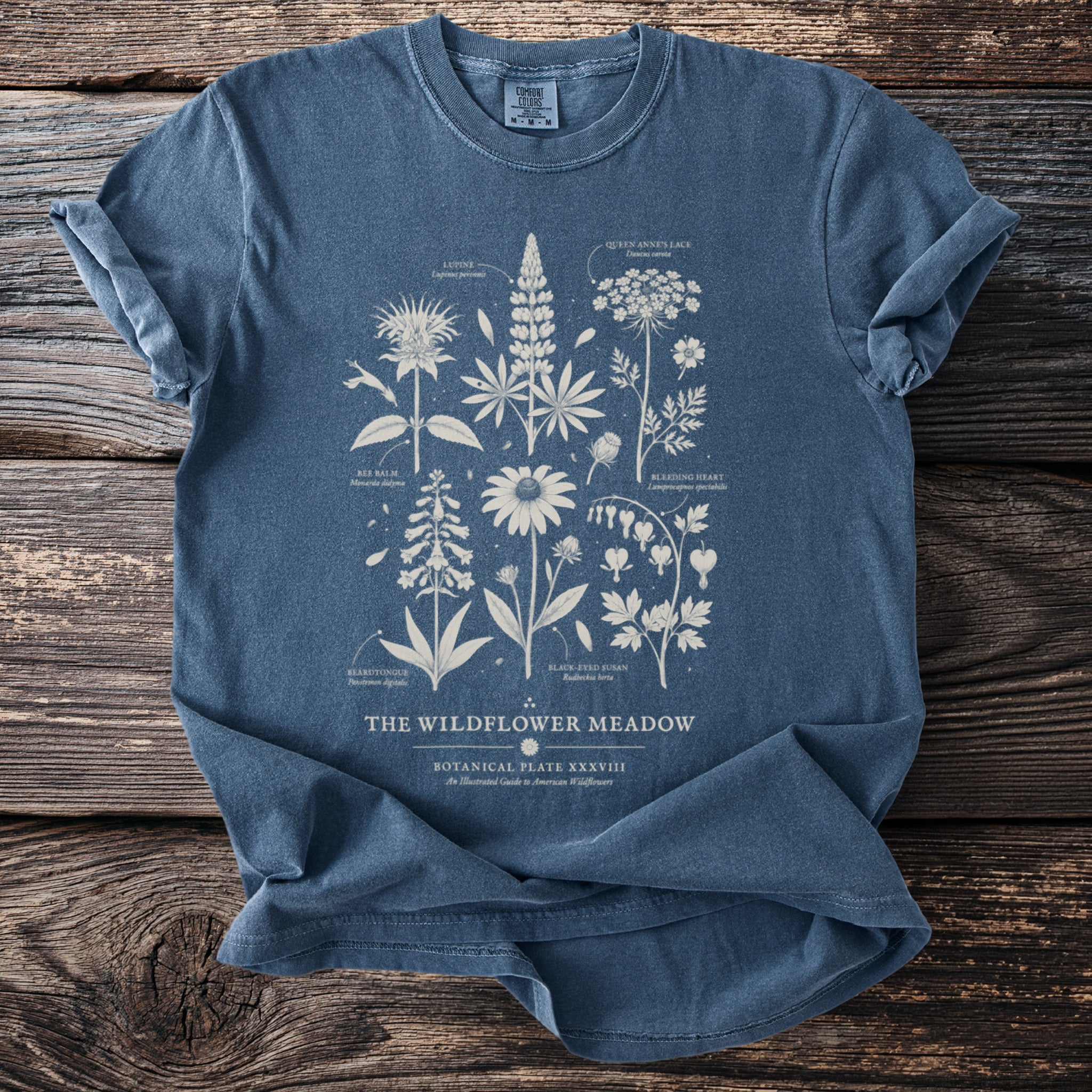 Blue t-shirt with "The Wildflower Meadow" botanical illustration and text.