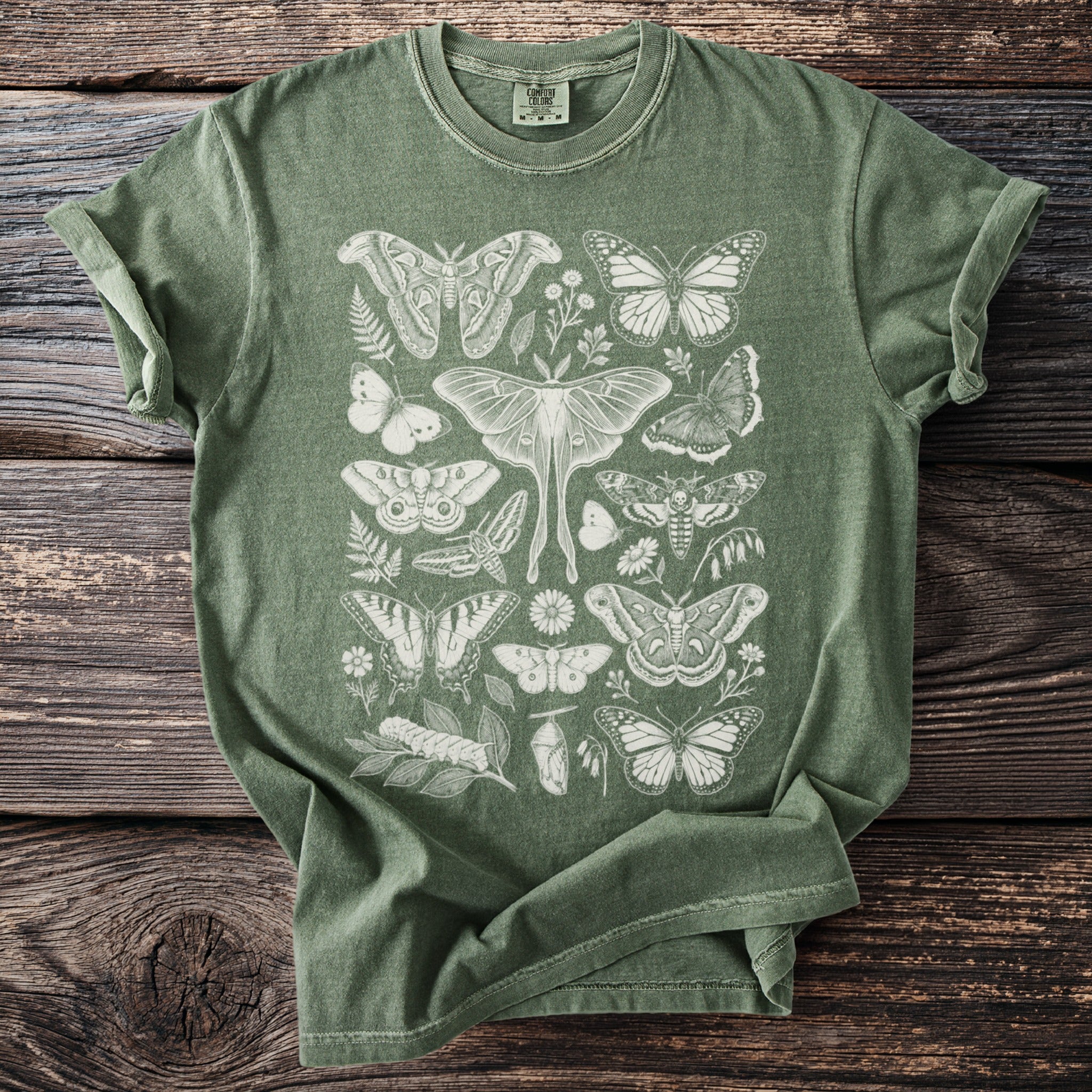 Green t-shirt with cream colored butterfly and moth illustrations.