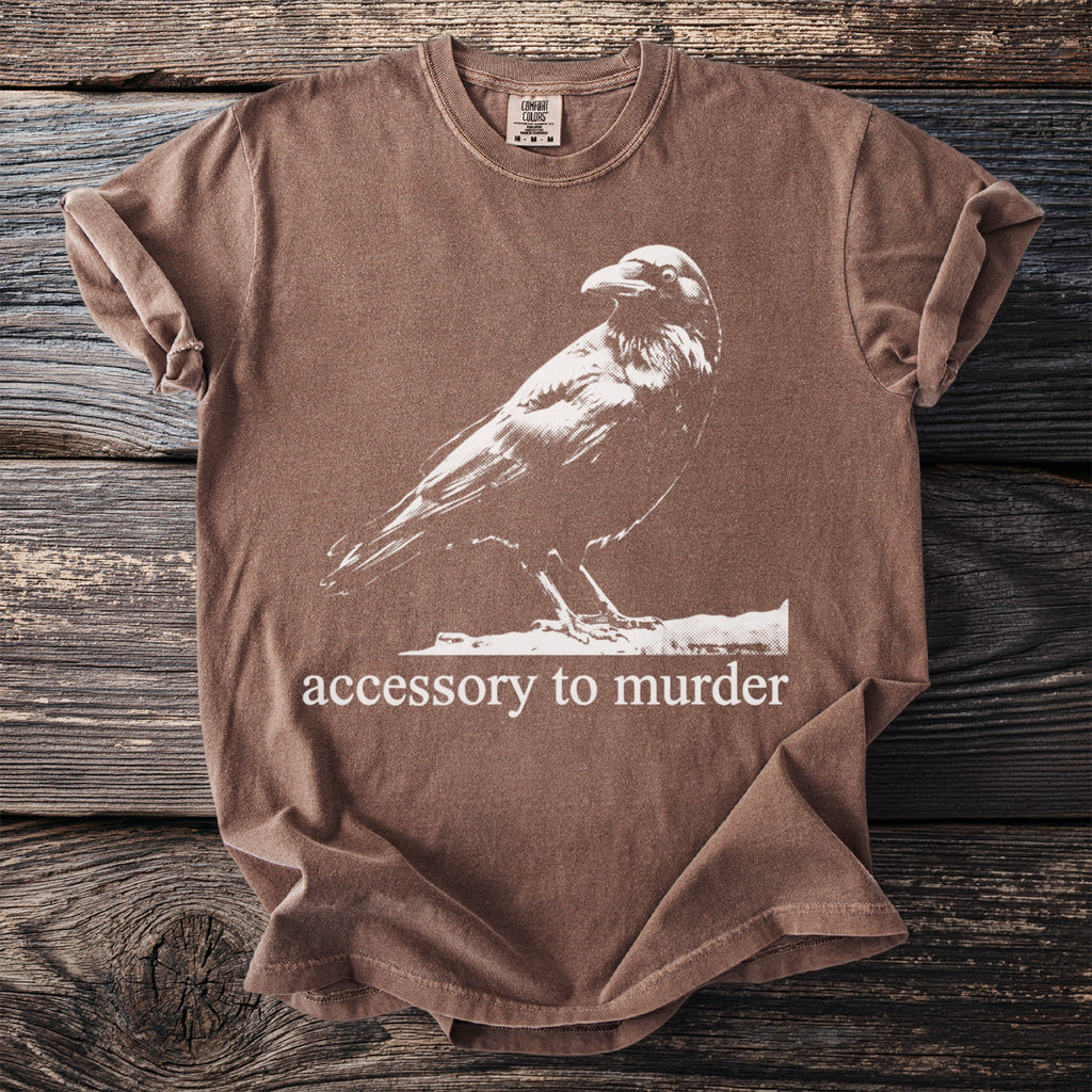 Brown t-shirt with graphic of a raven and text "accessory to murder".