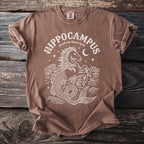 Brown t-shirt with white print of a hippocampus, wavy water, and a moon.