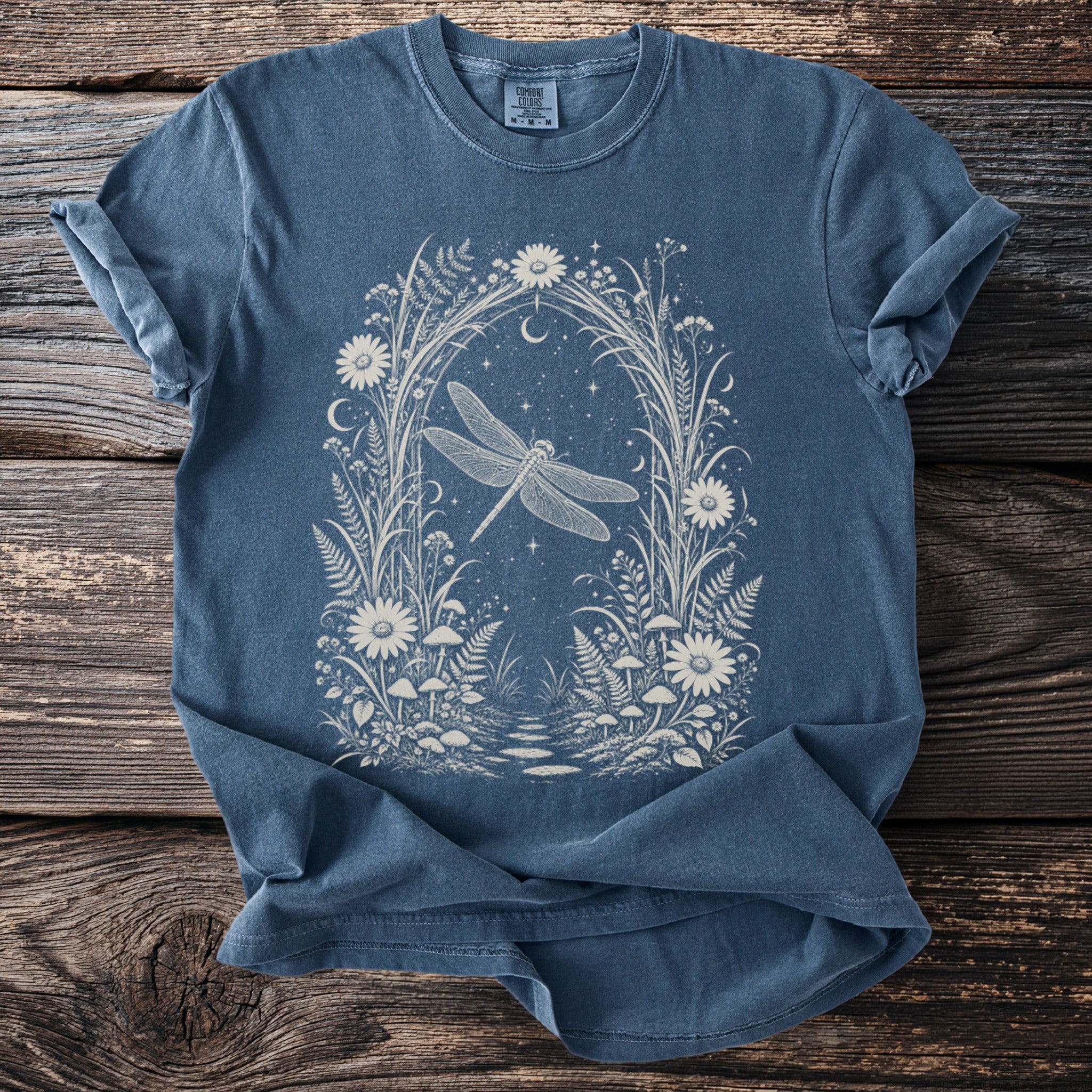 Blue comfort colors t-shirt with a white dragonfly and floral moonlit forest design.