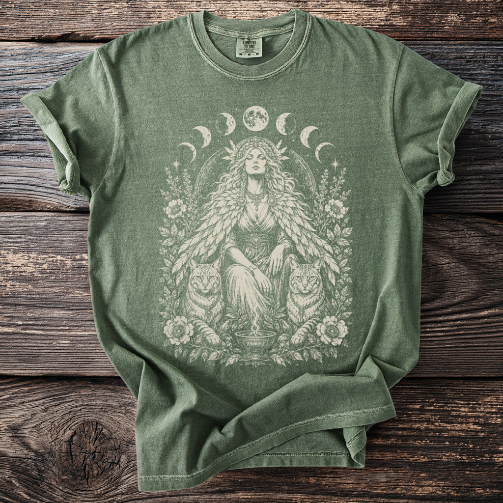 Green t-shirt with a circular design featuring a woman, cats, moons, and flowers.