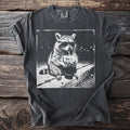 Black t-shirt with a sketch of a raccoon wearing sunglasses drinking from a cup.