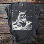 Black t-shirt with a sketch of a raccoon wearing sunglasses drinking from a cup.