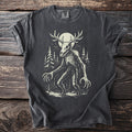Dark grey t-shirt with a skeletal creature with antlers and long claws in a forest.