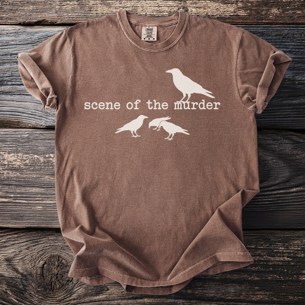 Brown t-shirt with white text "scene of the murder" and three crow silhouettes.
