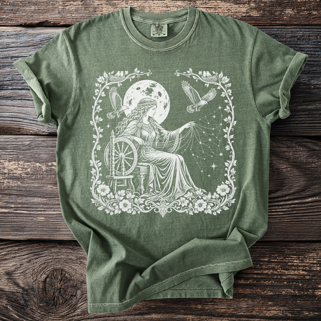 Olive green t-shirt with white graphic of woman spinning stars with eagles and moon overhead.