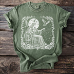 Olive green t-shirt with white graphic of woman spinning stars with eagles and moon overhead.