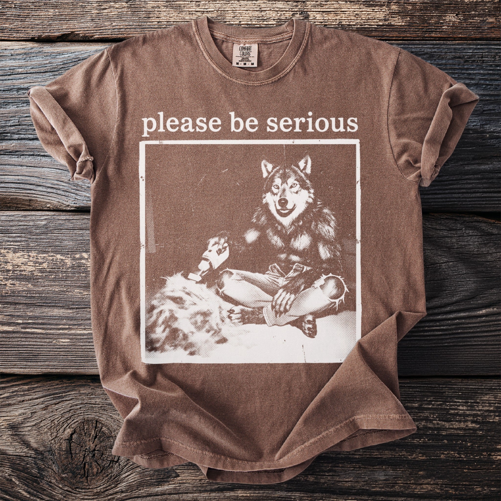 Brown t-shirt with "please be serious" and a wolf graphic.