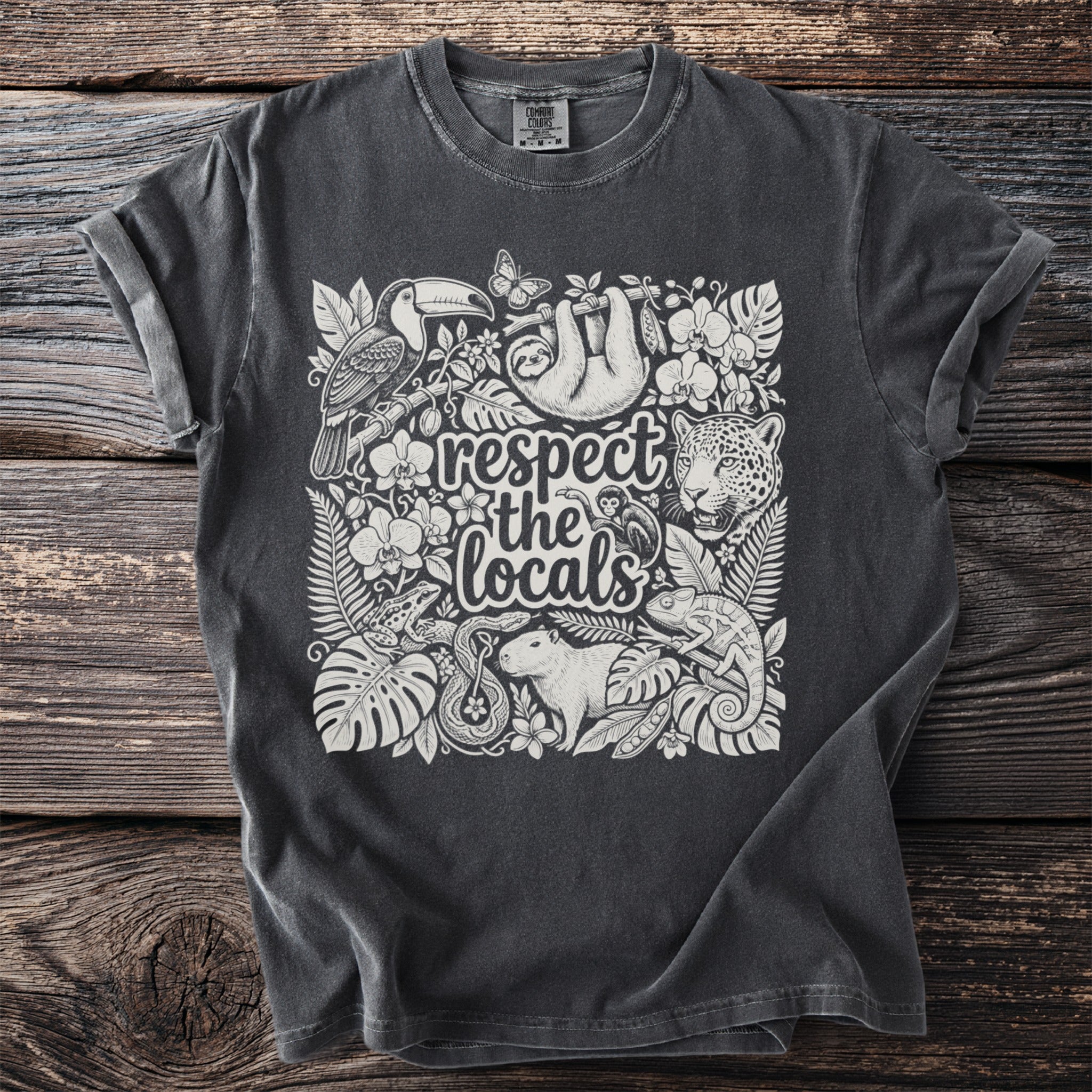 Dark grey t-shirt with a white artistic design of rainforest animals and plants.