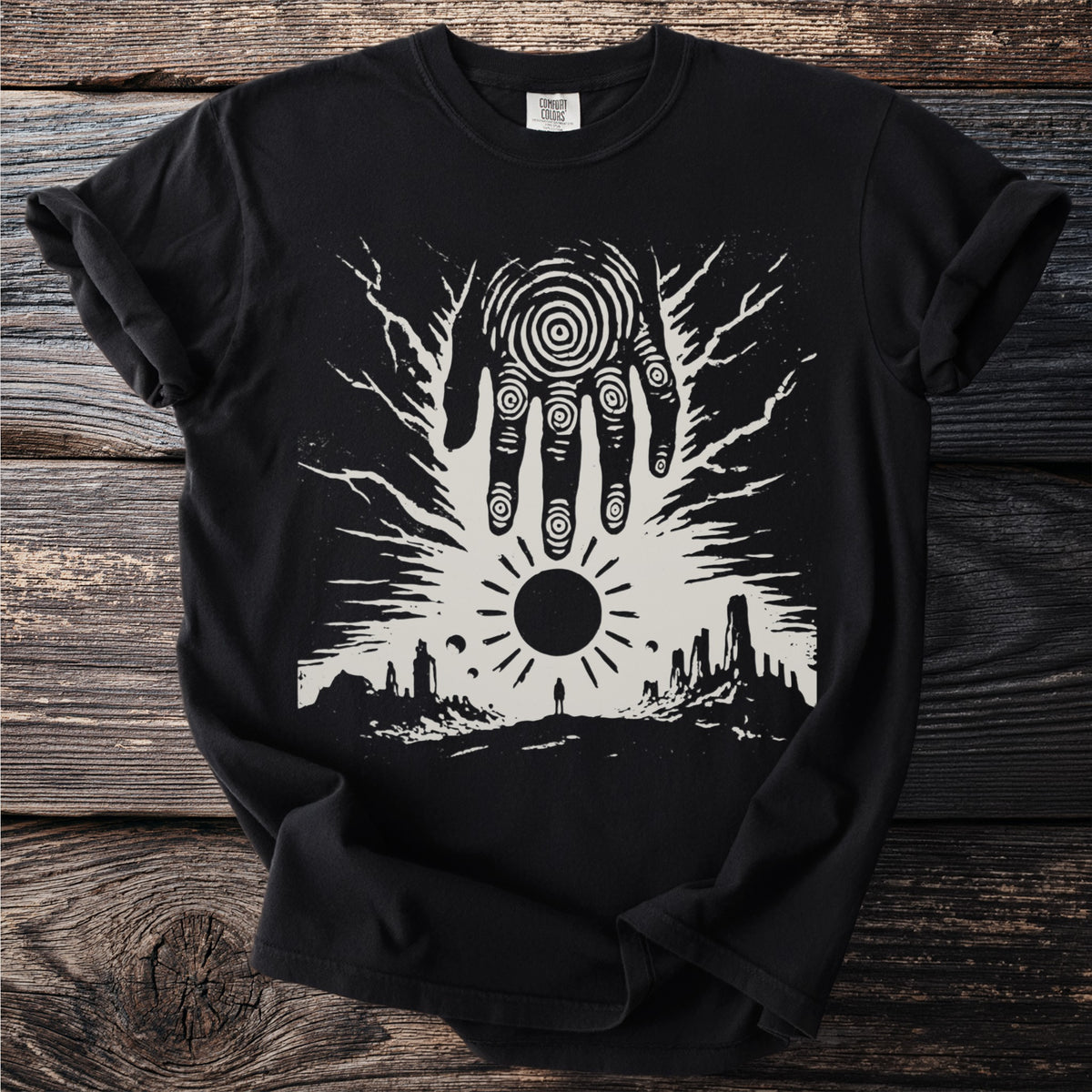 Black t-shirt with a surreal linocut print of a hand over a landscape.