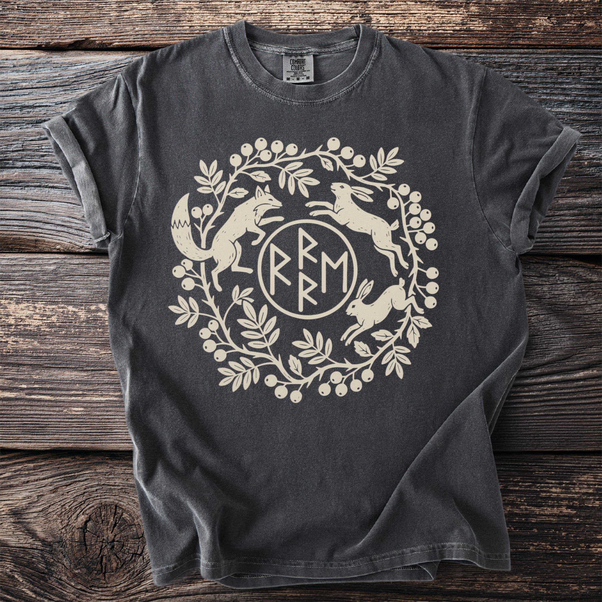 Dark t-shirt with cream-colored circular design of a fox, rabbits, and foliage.