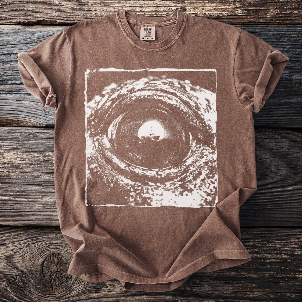 Brown t-shirt with a white graphic of a boat in a swirling tunnel.
