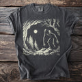 Dark t-shirt with a graphic of a creature in a forest under moonlight.