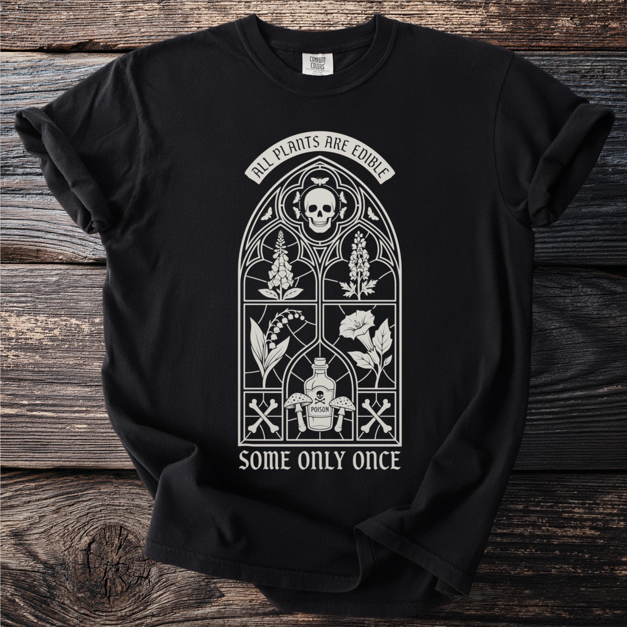 Black t-shirt with gothic window design, skull, plants, poison bottle, and text.