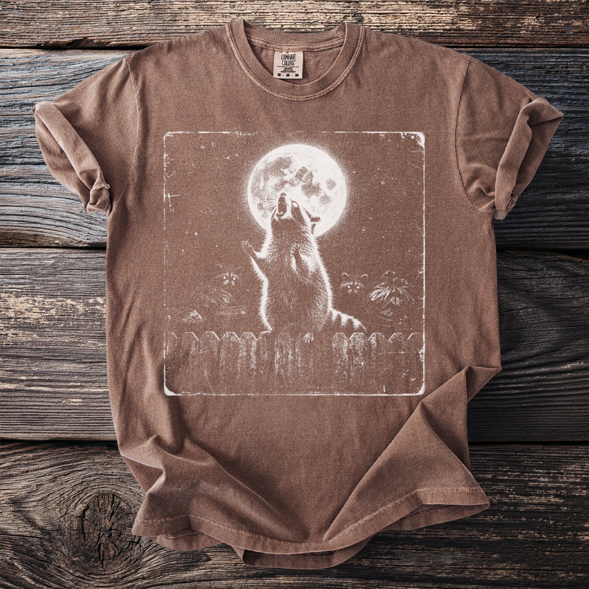 Brown t-shirt with a distressed graphic of a raccoon howling at the full moon.