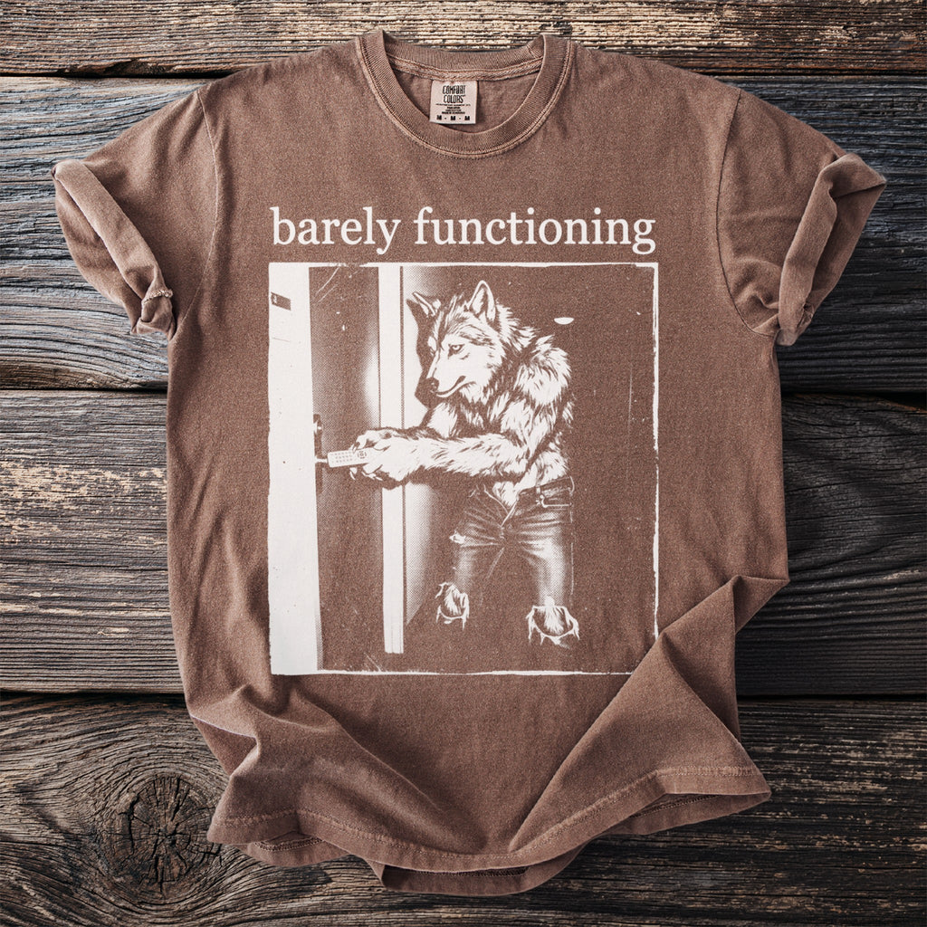 Brown t-shirt with "barely functioning" text and wolf graphic holding a remote.