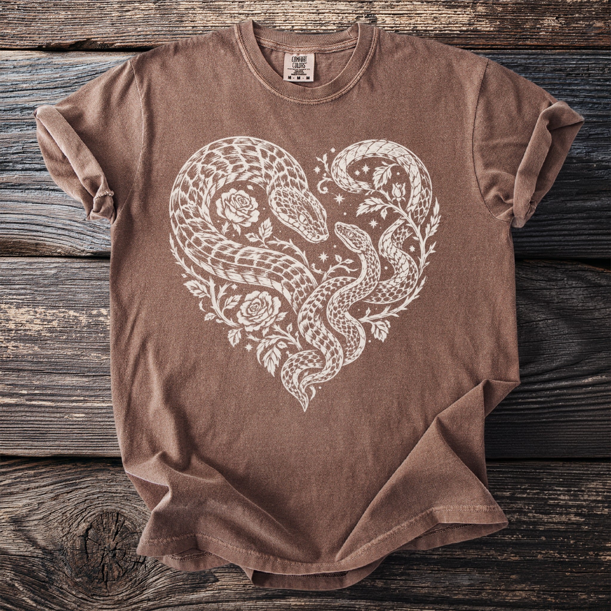Brown t-shirt with white heart design of intertwined snakes and roses.
