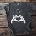 Dark t-shirt with a hooded figure, glowing eyes, hands forming a heart, and a moth.