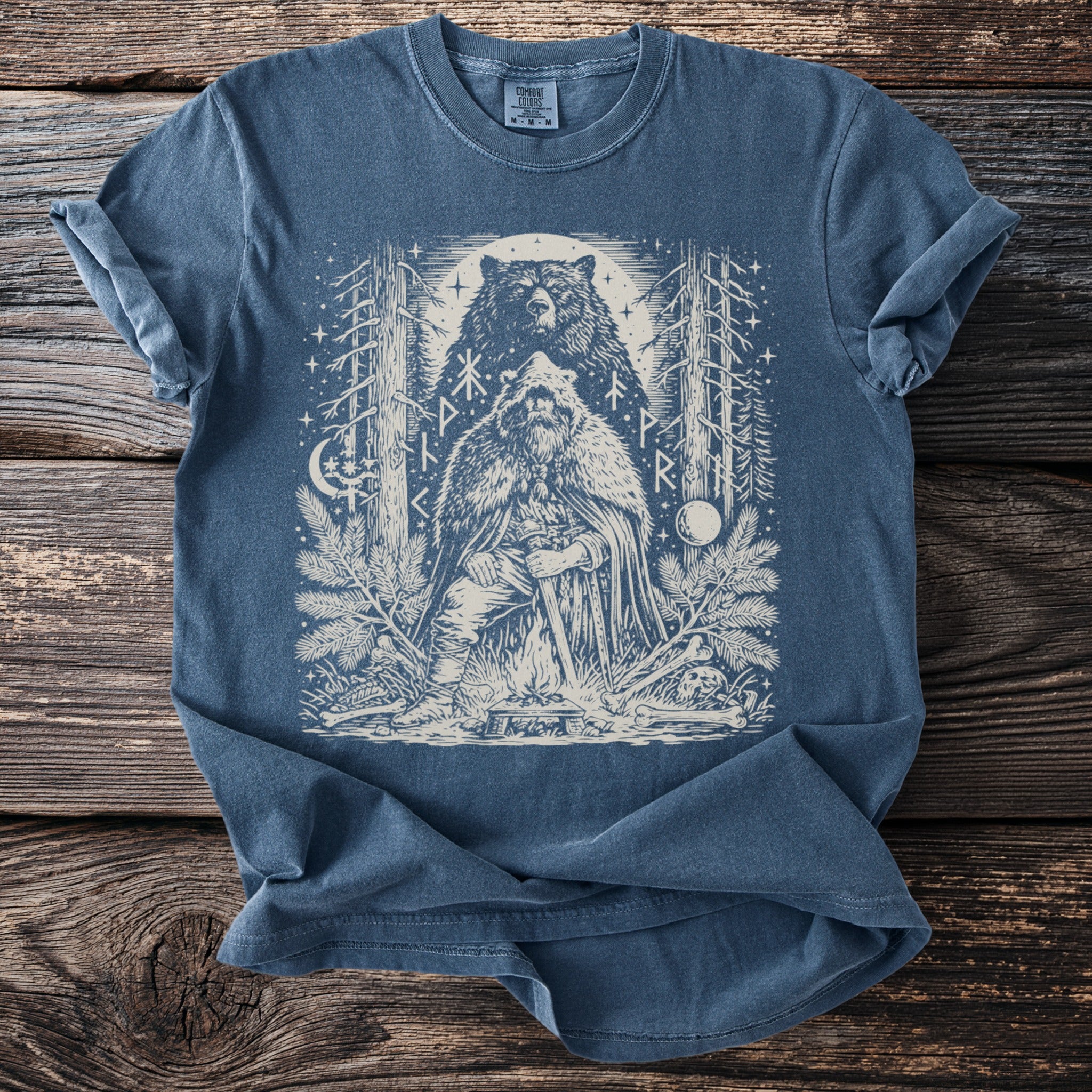 Blue t-shirt featuring a Viking warrior, bear, and runes in a forest setting.