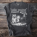 T-shirt with "Local cryptid support group" and drawings of raccoon, opossum, black cat, and frog.
