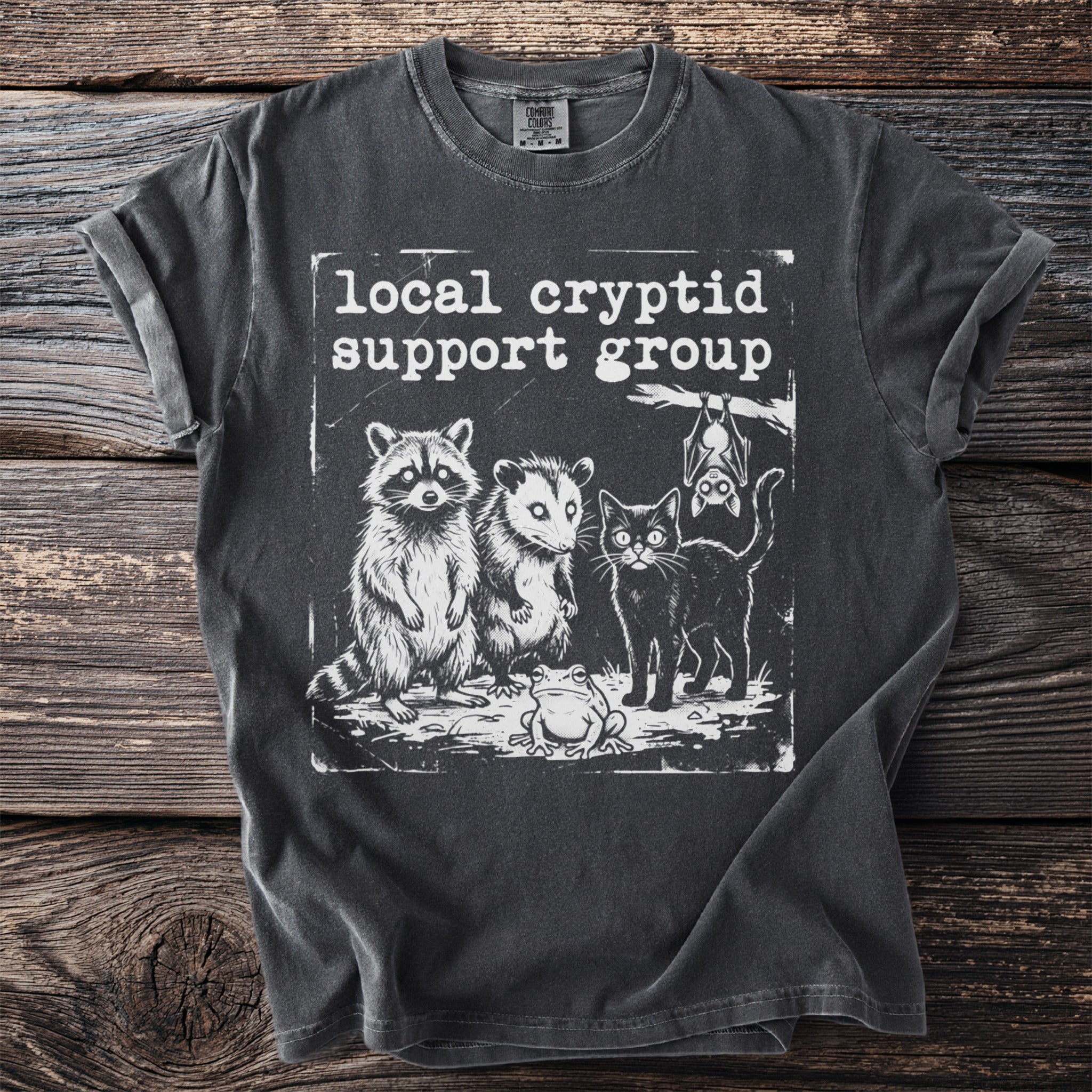 T-shirt with "Local cryptid support group" and drawings of raccoon, opossum, black cat, and frog.