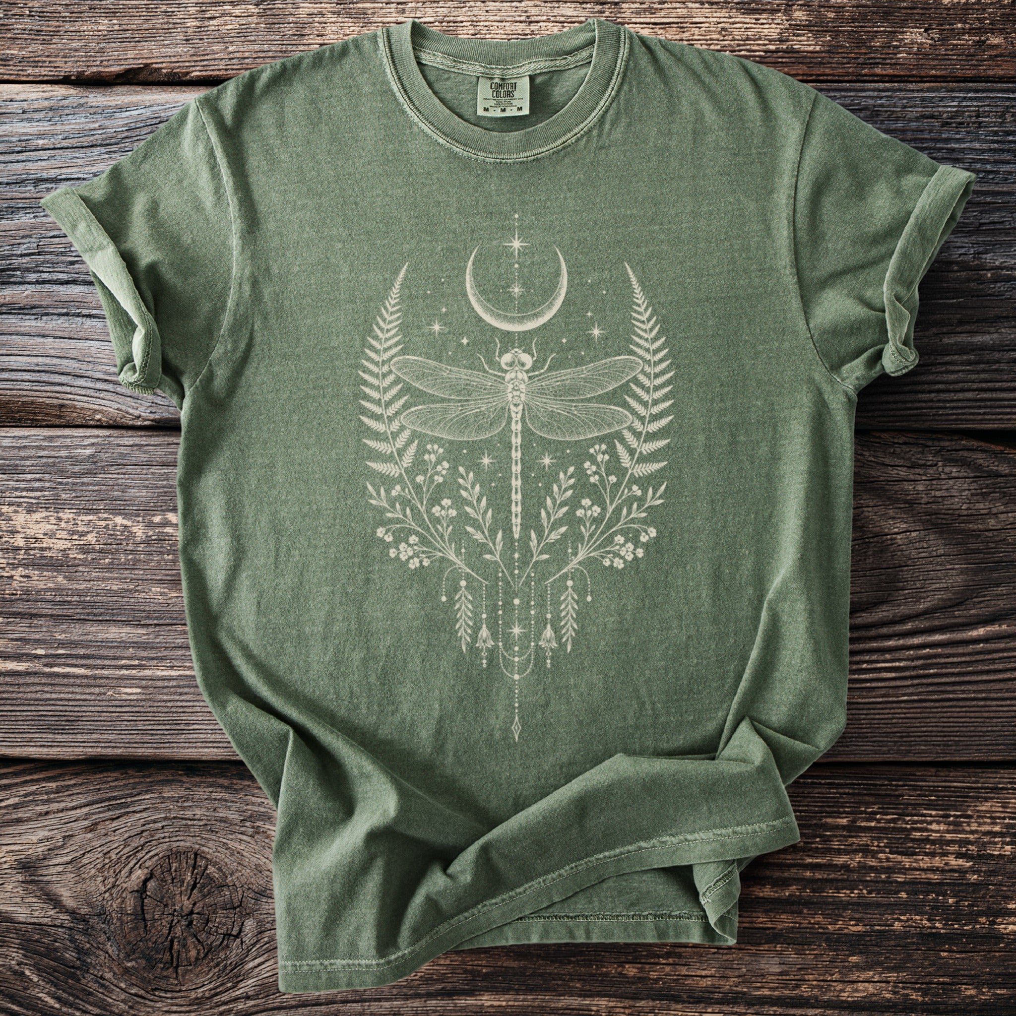 Green t-shirt with a central cream-colored dragonfly and celestial botanical design.