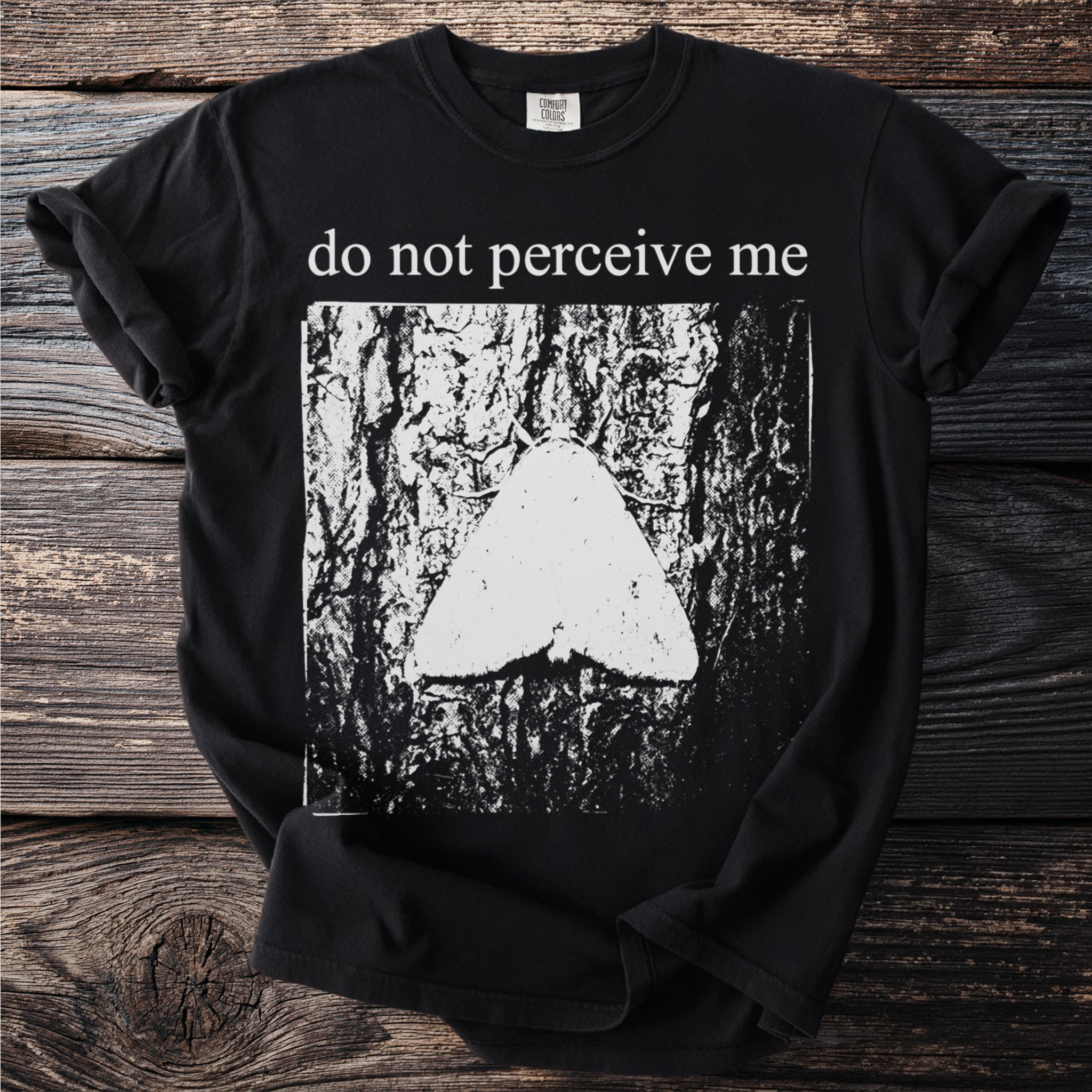 Black t-shirt with white text "do not perceive me" and moth on bark graphic.