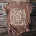 Brown t-shirt with a vintage sketch of a witch stirring a cauldron with a raven nearby.