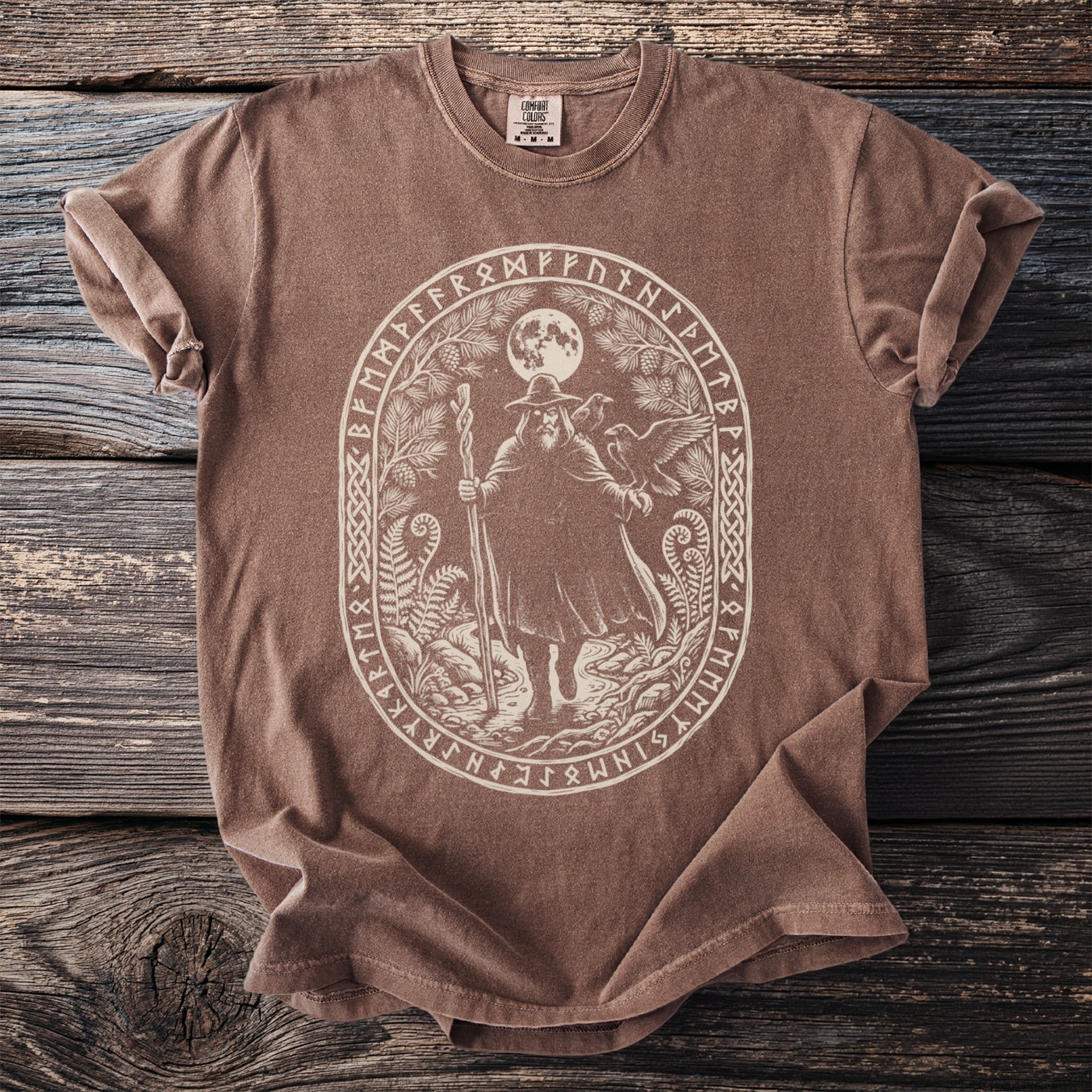 Brown t-shirt with an oval print of a wizard, ravens, and runes under a moon.