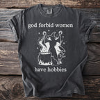 Dark gray t-shirt with white text "god forbid women have hobbies" and witch graphic.